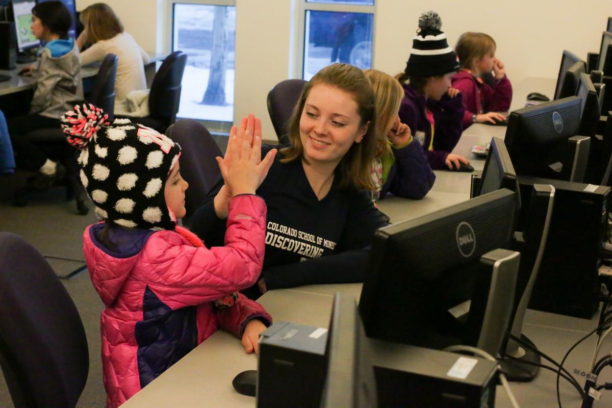 Female student works with a young girl.